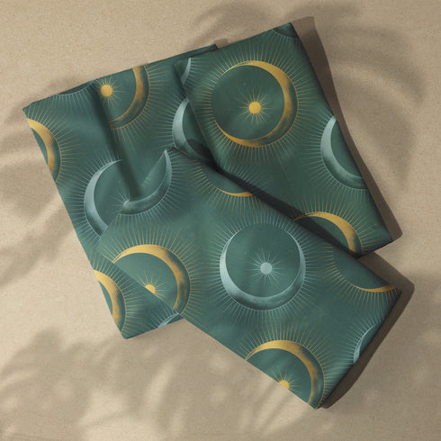 Four-piece cloth napkin set featuring a celestial print of radiant golden crescent moons and pale sunburst orbs against a rich emerald green background. Each napkin displays symmetrical, glowing motifs inspired by lunar phases and cosmic geometry. The fabric is neatly folded to showcase the repeating pattern, with a soft matte finish and fine detailing, perfect for mystical or magical table settings, altar decor, or celestial-inspired dining aesthetics.